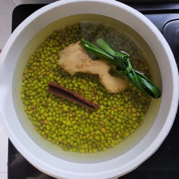 Rebus kacang hijau dengan air. Ttambahkan daun pandan, kayu manis, dan jahe yang sudah digeprek. Rebus hingga kacang hijau benar-benar empuk.