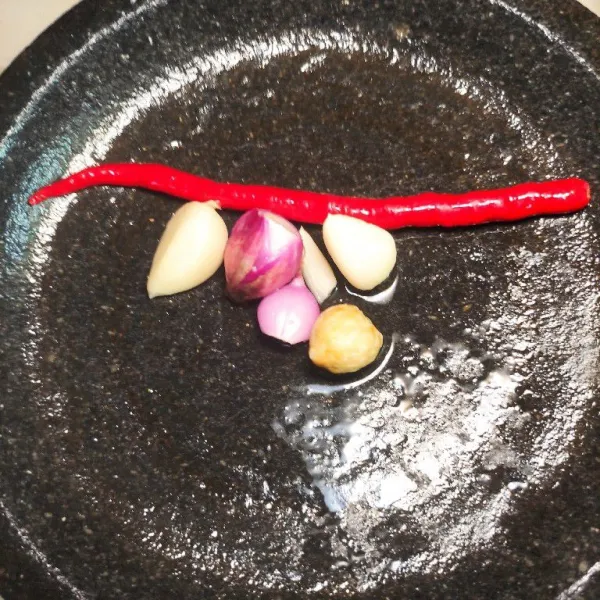 Haluskan bawang putih, bawang merah, kemiri, dan cabai keriting merah.