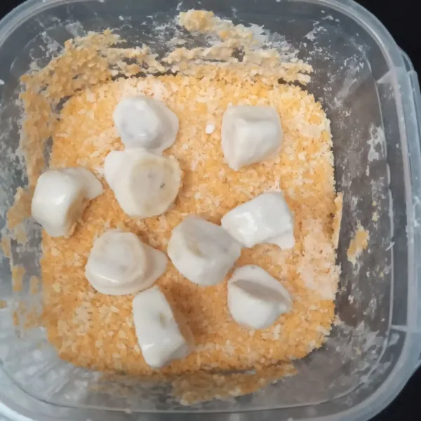 Ambil tiap potong pisang yang telah dibalut tepung basah, lalu gulirkan ke tepung roti.