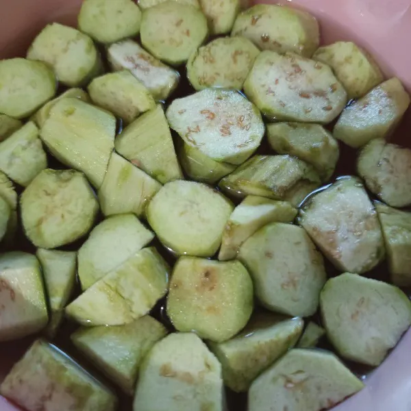 Kupas terong, kemudian potong-potong. Masukkan ke dalam wadah berisi air dan sedikit garam, lalu rendam.