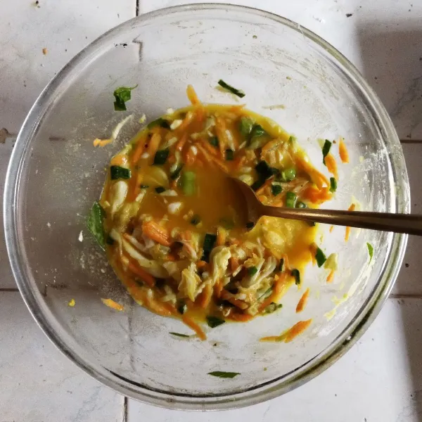 Siapkan wadah. Campurkan kol, bawang bombay, wortel parut, daun bawang, telur, bumbu kare, garam, kaldu ayam, dan lada. Kemudian, aduk rata.