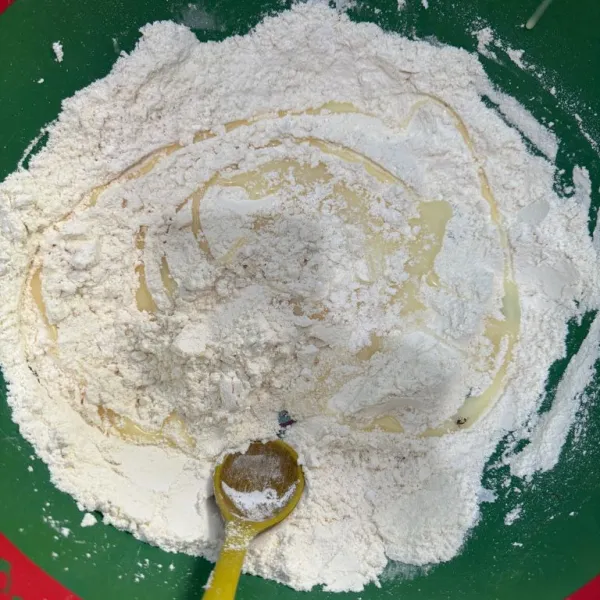 Tambahkan kental manis dan vanilla ekstra, aduk kembali. Tambahkan air hangat. Aduk sampai tercampur, tidak lengket, dan bisa dibentuk.