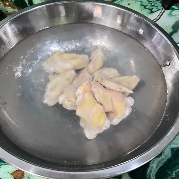 Jika air sudah mendidih, masukkan sayap ayam, lalu rebus hingga matang.