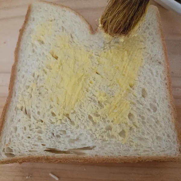 Tutup dengan roti lainnya, lalu bagian atas permukaan diolesi margarin.