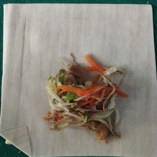Ambil selembar kulit lumpia, lalu atasnya beri isian kecambah. Lipat dan rekatkan dengan putih telur.