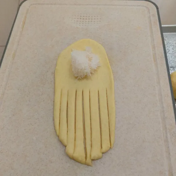 Ambil satu adonan, lalu pipihkan, beri isian unti kelapa, lalu potong sisi lainnya seperti gambar