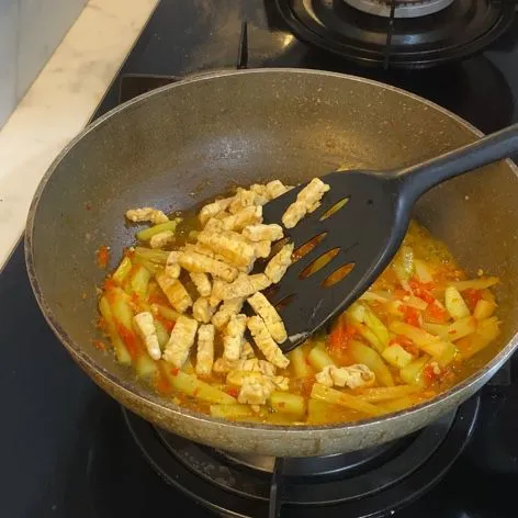 Ketika labu siam sudah setengah matang, masukkan tempe.