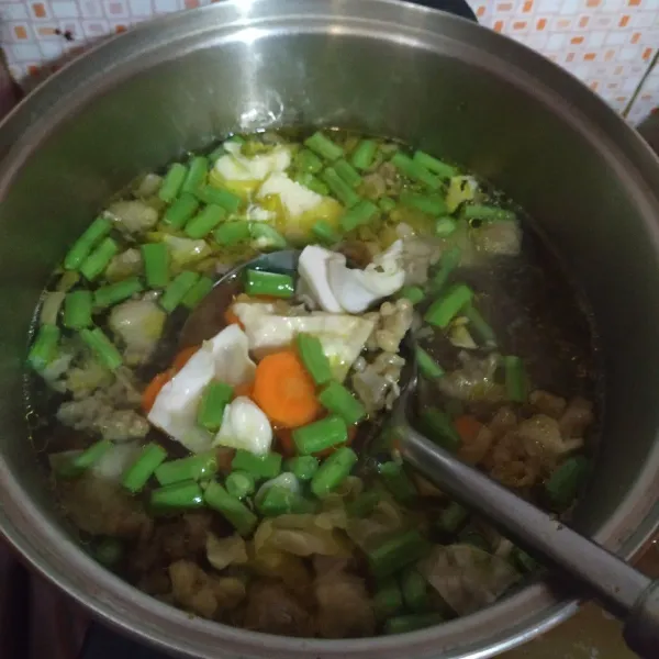 Masukkan seledri, wortel, buncis, dan kol. Bumbui dengan garam, lada bubuk, dan kaldu bubuk. Masak sampai sayuran empuk dan koreksi rasa.