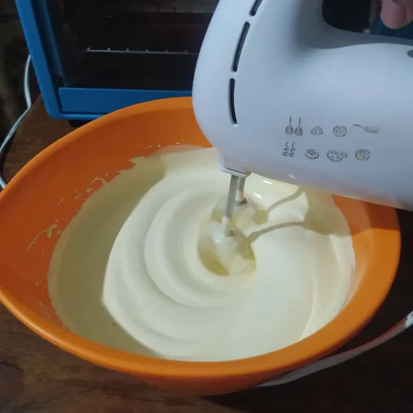 Kocok gula dan telur, setelah mulai mengembang masukkan emulsifier. Kocok terus sampai putih kental dan berjejak.