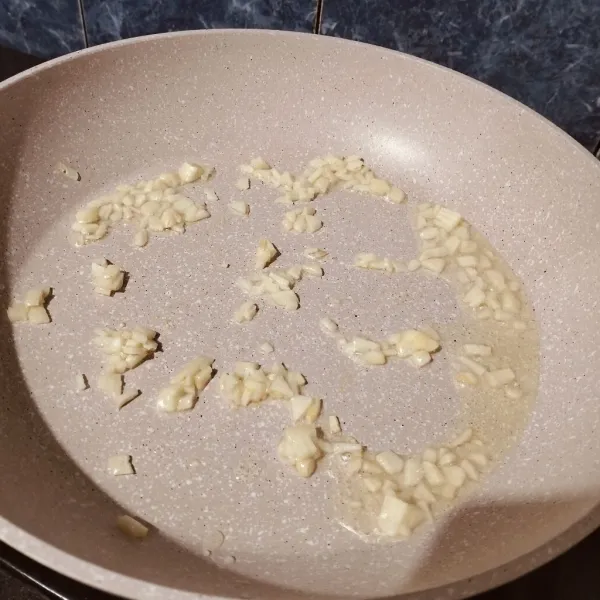 Tumis bawang putih sampai layu dan harum.