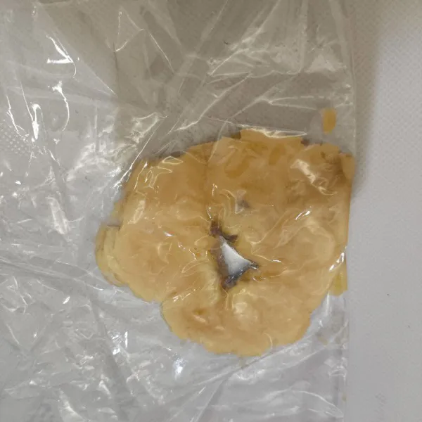 Potong-potong pisang menjadi beberapa bagian, apasi pisang dengan plastik lalu penyet menggunakan talenan.