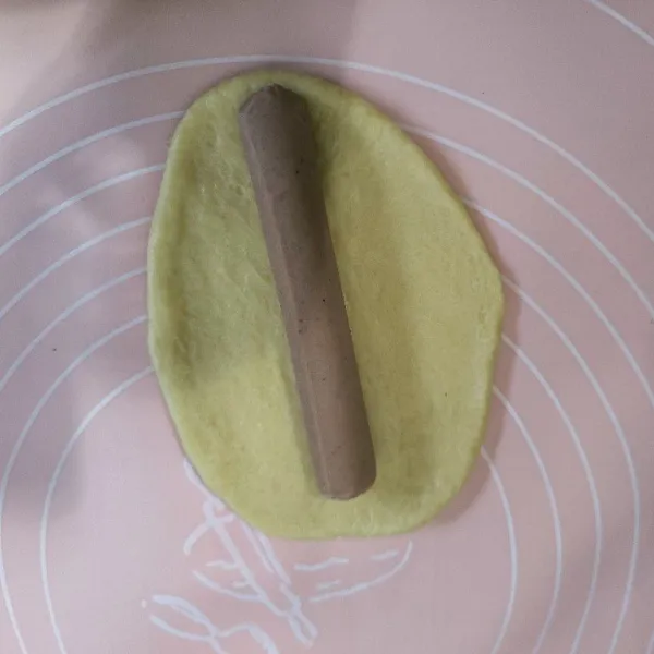 Ambil satu buah adonan kemudian pipihkan dan tambahkan sosis bagian tengahnya.