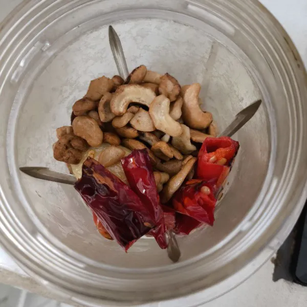 Masukkan kacang mente sangrai, cabe merah, dan bawang putih goreng ke dalam blender.