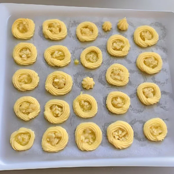 Sendokkan karamel almond ke atas adonan kue. Panggang dalam oven  panas pada suhu 160°C. Gunakan api atas bawah, dan panggang selama 25 menit.