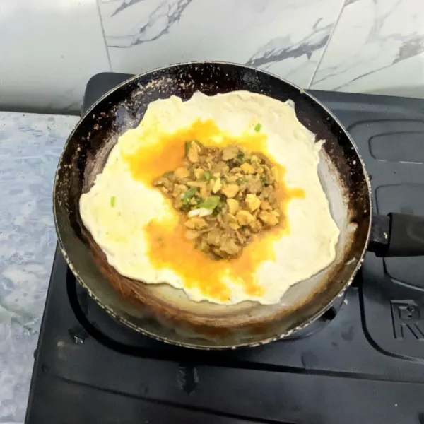 Ambil kulit lumpia, lalu masukkan isian. Tutup rapat pada keempat bagian sisi hingga membentuk lipatan martabak.