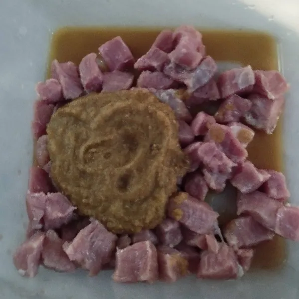 Tuang bumbu halus ke dalam wadah yang berisi daging kambing.