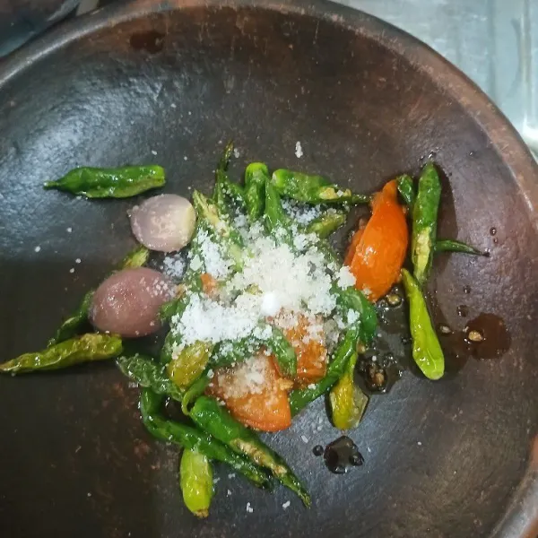 Setelah layu, angkat, letakkan diatas ulekan, bumbui dengan garam dan gula pasir. Lalu ulek kasar.