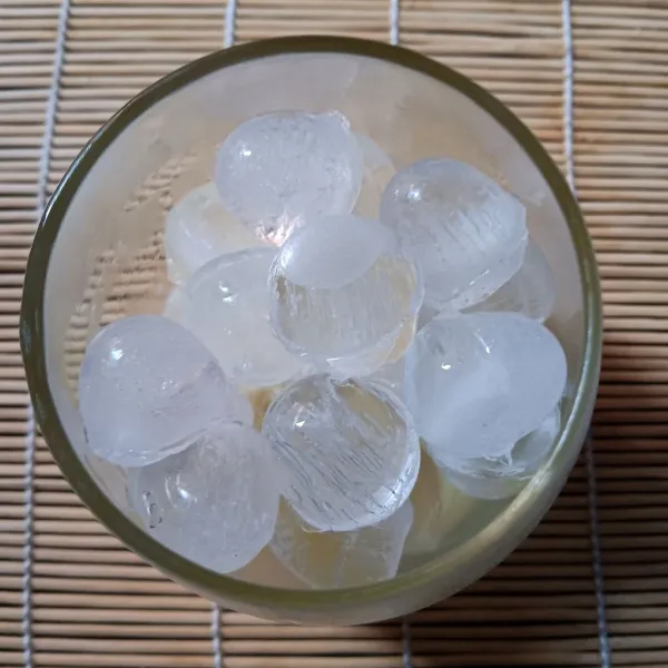 Tuang krimer kental manis kedalam gelas saji. Tambahkan es batu.