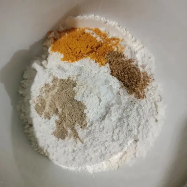 Dalam wadah, campur terigu, tepung beras, ketumbar bubuk, kunyit bubuk, merica bubuk, garam, aduk rata.