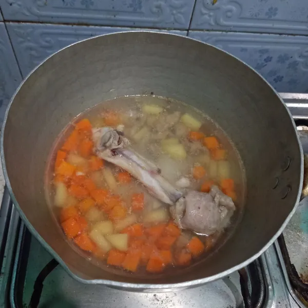 Didihkan air, lalu masukkan tulang paha ayam sebagai penyedap. Masukkan juga wortel dan kentang.
