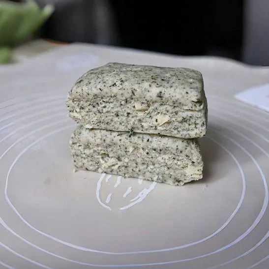 Tuangkan 60 ml susu cair sedikit demi sedikit sambil diaduk sampai adonan menyatu dan bisa dipulung. Keluarkan adonan, pipihkan perlahan setebal 1,5 cm.