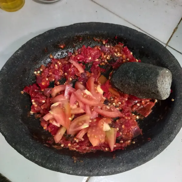 Tambahkan irisan tomat, lalu uleg perlahan.