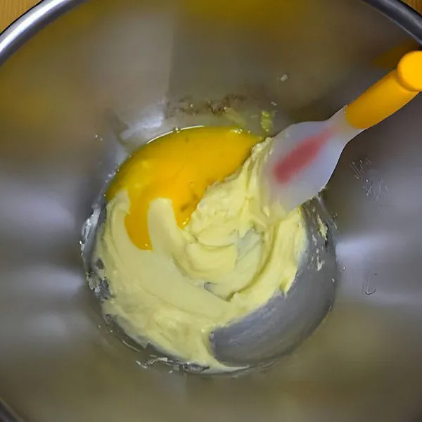 Dalam wadah lain, campurkan mentega dan gula halus, aduk hingga lembut dan rata. Tambahkan telur, aduk rata.