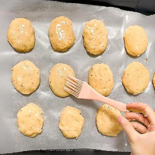 Olesi permukaan adonan dengan minyak secara merata. Panaskan oven selama 5 menit pada suhu 200°C. Panggang adonan di suhu 200°C selama 25 menit.