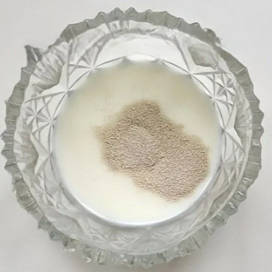 Campurkan susu hangat dengan ragi instan dalam mangkuk. Aduk rata hingga ragi larut.