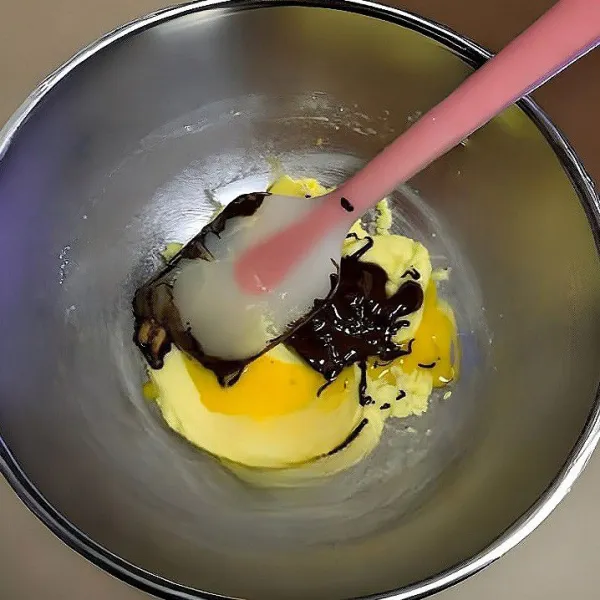 Campurkan mentega dan gula halus, aduk hingga lembut dan tercampur rata. Tambahkan telur, aduk hingga merata. Masukkan saus cokelat leleh, aduk kembali hingga rata.