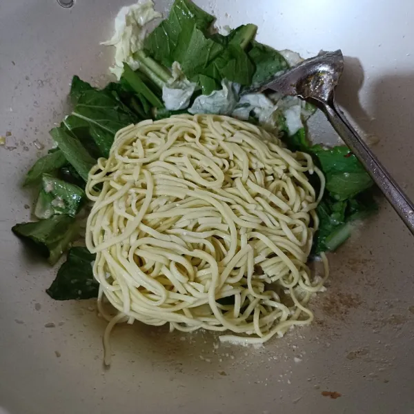 Masukkan mi dan sedikit air kaldu, aduk rata