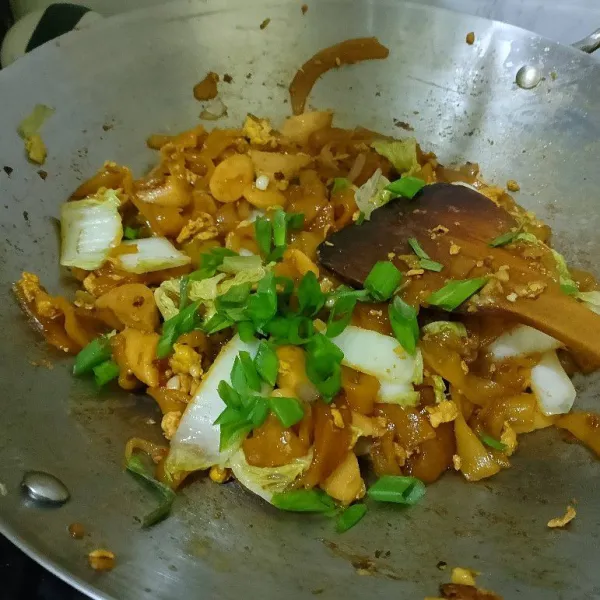 Masukkan kwetiau, lalu masak dan aduk rata. Jangan lupa untuk koreksi rasa. Tambahkan daun bawang dan lanjut diaduk hingga matang.