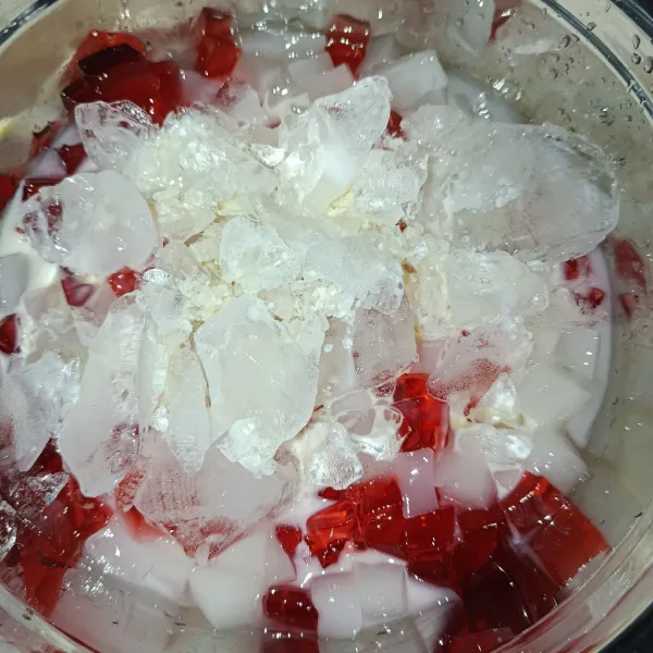 Siapkan wadah besar, masukkan jelly yang sudah di potong tadi, susu kental manis, susu evaporasi dan es batu.