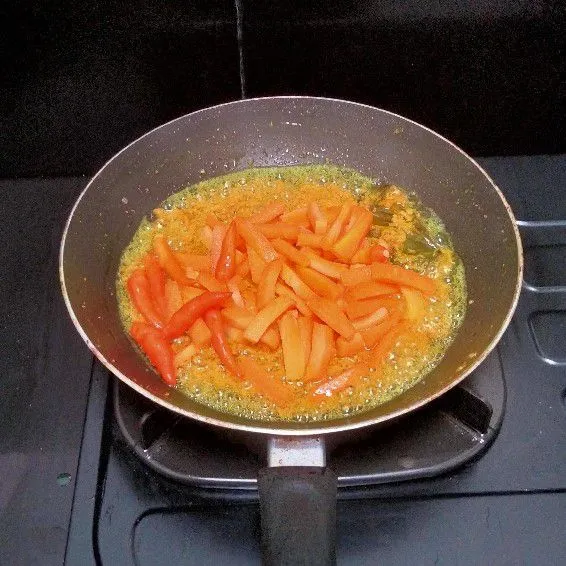 Langkah keempat, tambahkan irisan wortel dan cabai rawit utuh lalu aduk hingga tercampur rata. Setelah itu tambahkan air secukupnya dan masak hingga wortel setengah matang.