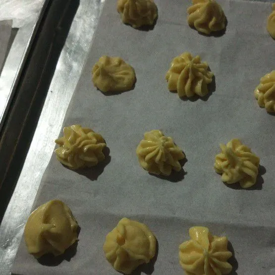 Tempatkan dalam plastik kue segitiga, lalu cetak di loyang yang sudah dilapisi kertas roti.