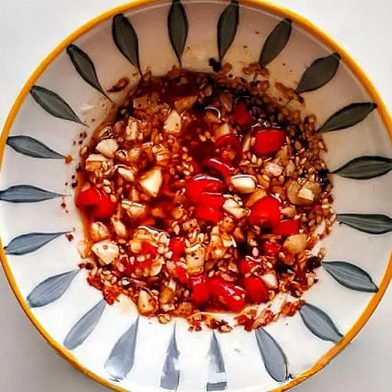 Campurkan bawang putih cincang, cabe rawit cincang, wijen putih sangrai, dan bubuk cabe kering ke dalam mangkuk. Siram dengan minyak panas, aduk rata.