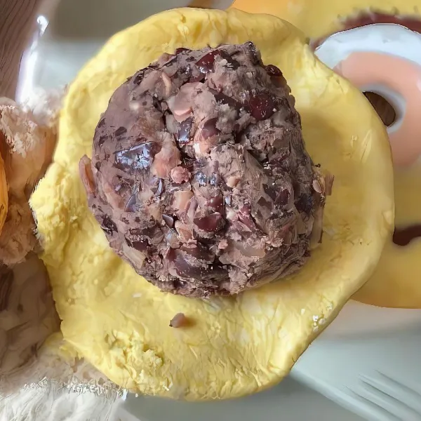 Ambil adonan kulit, pipihkan, lalu beri isian pasta kacang merah dan bulatkan rapat.