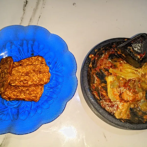 Tiriskan terong, campurkan dengan sambal yang sudah dihaluskan. Sajikan bersama tempe goreng selagi hangat.