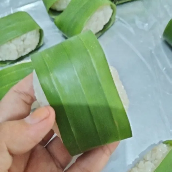 Bungkus bagian tengah dengan daun pisang, lalu gulung dengan daun pisang dan sematkan lidi. Lemper bisa dibakar terlebih dahulu atau langsung disajikan.