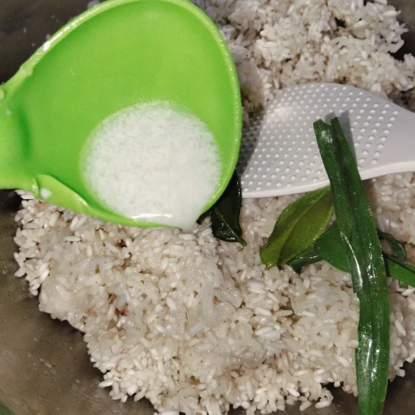 Tuangkan santan ke dalam beras ketan yang sudah dikukus.