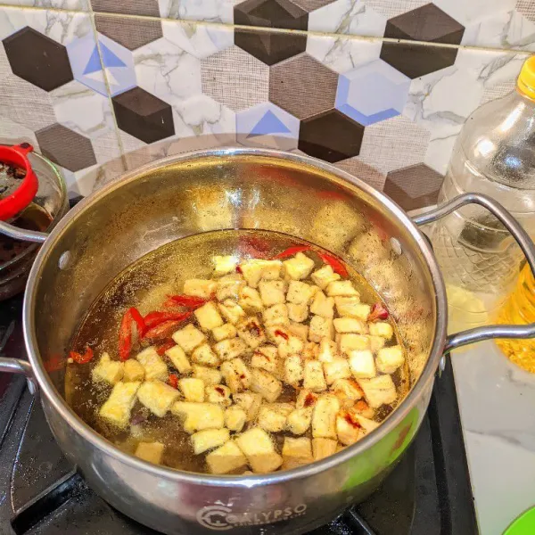 Tambahkan air, tahu yang sudah digoreng, kecap, garam, dan kaldu bubuk.