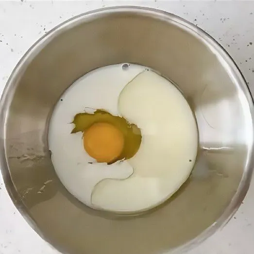 Campurkan 1 butir telur, susu cair, dan minyak jagung ke dalam wadah, lalu aduk hingga rata.