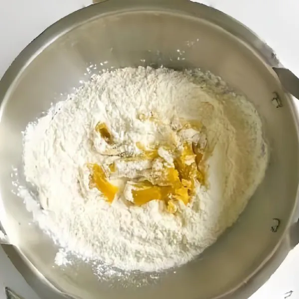 Campurkan tepung terigu, gula pasir, dan puree labu kuning. Aduk hingga menjadi adonan remah.