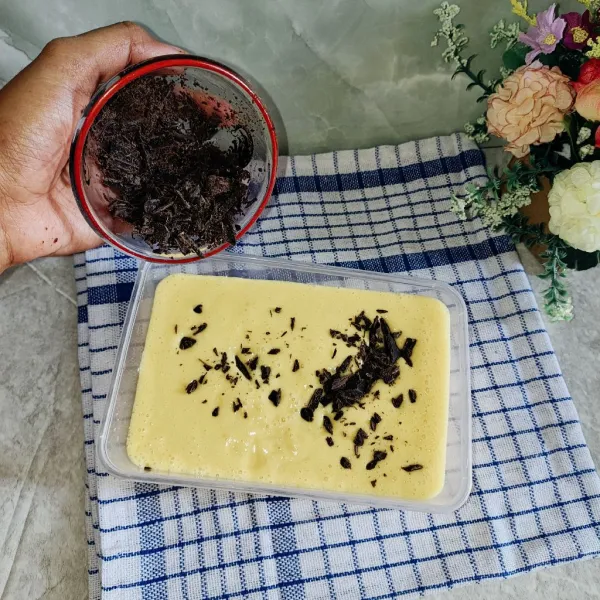Tambahkan potongan cokelat batang, lalu aduk perlahan dan simpan ke dalam freezer selama 3–4 jam hingga set dan membeku.
