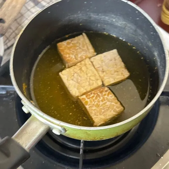 marinasi tempe dengan cara mencampur kunyit bubuk, bawang putih bubuk, ketumbar bubuk, garam, penyedap, lada bubuk dan air. Lalu hidupkan kompor marinasi tempe sampai bumbu meresap ke dalam tempe.