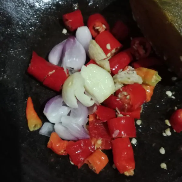 Haluskan bawang merah, bawang putih, kemiri, cabe merah besar, dan cabe rawit menggunakan ulekan.