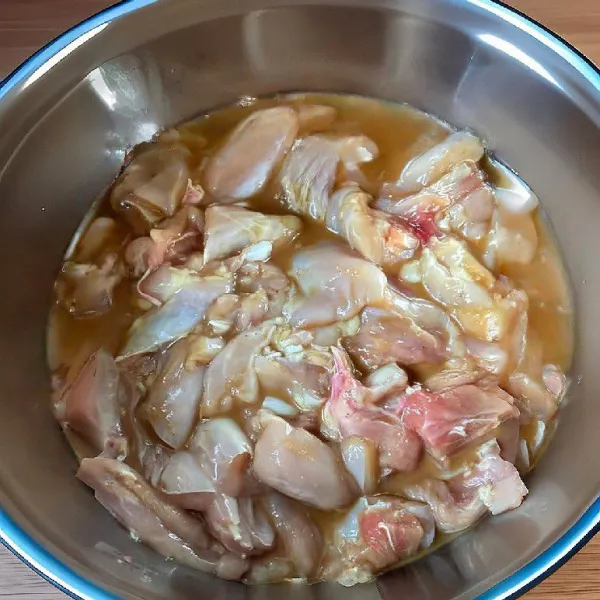 Campurkan daging paha ayam dengan arak masak, kecap asin, minyak wijen, lada putih bubuk, dan tepung maizena. Aduk rata dan diamkan selama 15 menit.
