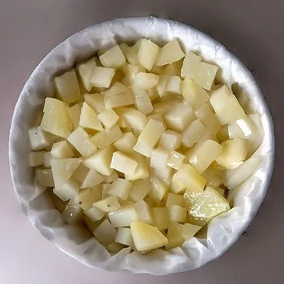 Kukus sebentar kentang dadu kecil hingga setengah matang, lalu letakkan di dasar loyang tahan panas