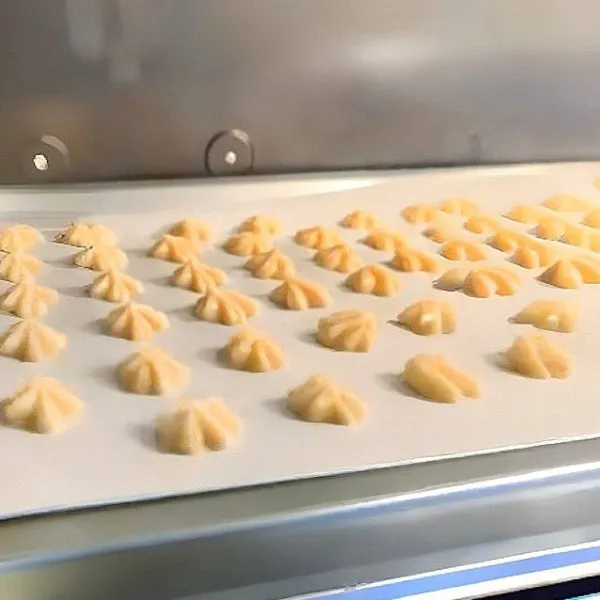 Masukkan adonan ke dalam piping bag, semprotkan membentuk bunga kecil di atas loyang. Panggang dalam oven suhu 200°C selama 10 menit, lalu turunkan suhu ke 170°C selama 15 menit.