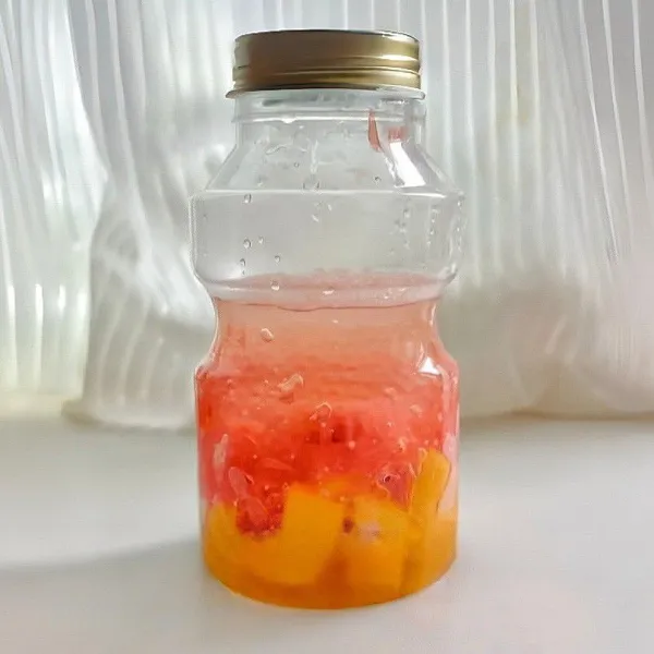 Letakkan potongan mangga di dasar botol saji, lalu tambahkan sagu mutiara dan jeruk bali di atas potongan mangga.